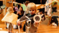A Paper Planet production image. A child unrolls a roll of tape, looking at the tape intently. Photo: Katje Ford.