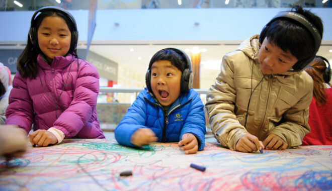 Three kids drawing with headphones on