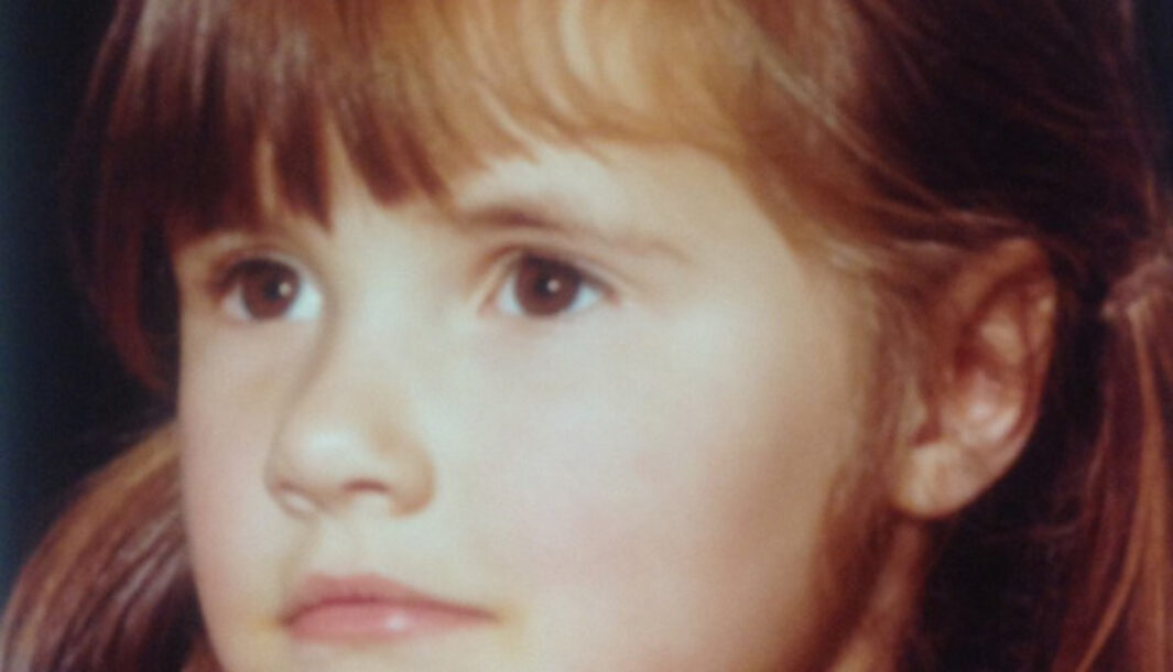 A child with brown eyes and shoulder length brown hair looks forward.