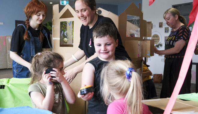 A Cubbyhood photo. Polyglot artists and small children create and play among cardboard box cubbies. Photographer: Suzanne Phoenix