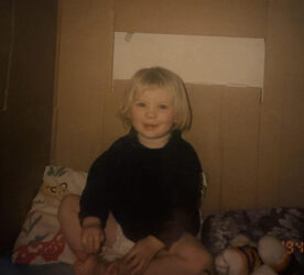 A child with blonde hair smiles at the camera.