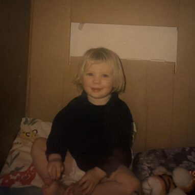 A child with blonde hair smiles at the camera.