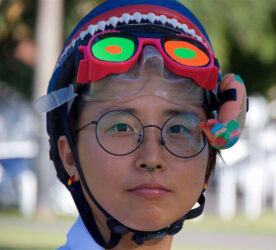 A person wears a knitted helmet, multicoloured goggles and glasses. Photo by Jean-Ettien Parrot.