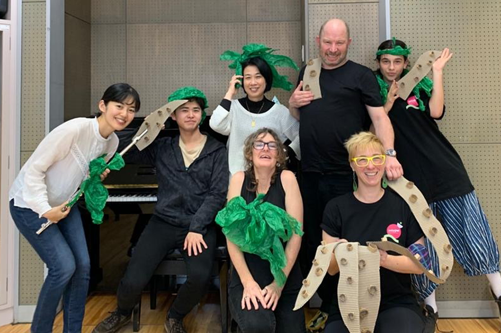 A 2023 group photo of Polyglot and Acchi Cocchi artists, wearing handmade paper costumes and smiling.