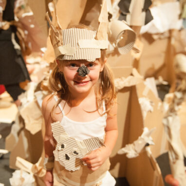A Paper Planet production photo: A child wears a paper costume and mask against the backdrop of the set. Photo: Sarah Walker