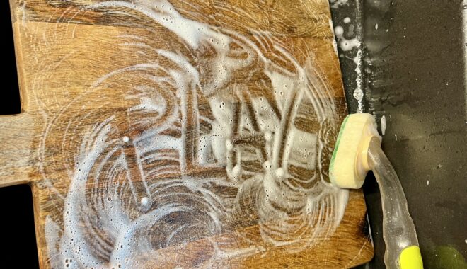 Photo: Lauren Swain. The word 'play' written in dishwashing foam on a wooden chopping board.
