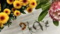 Photo: Lauren Swain. The word 'play' formed out of flowers and leaves on a white tablecloth.