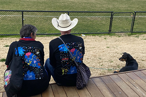 A Rumbalara Game Day workshop. Two people wear Rumba t-shirts. There is a black dog to the right. Photo: Lexie Wood.