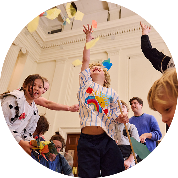 Whirlwind production photo: A child in a dinosaur t-shirt holds a paper kite and gazes up above. Photo: Laura May Grogan.