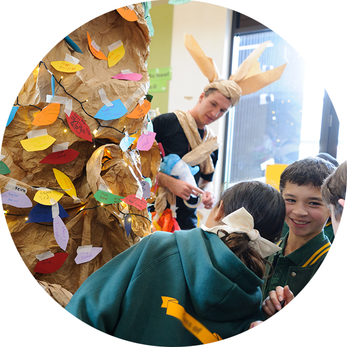 Wish Street production photo: Children gather around the Wish Street tree. There is a Polyglot artist wearing a paper costume in the background. Photo: Sarah Walker.