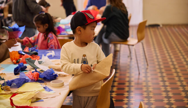 Whirlwind production photo: Laura May Grogan. A child in a cap creates and plays with paper and tape at the making table.