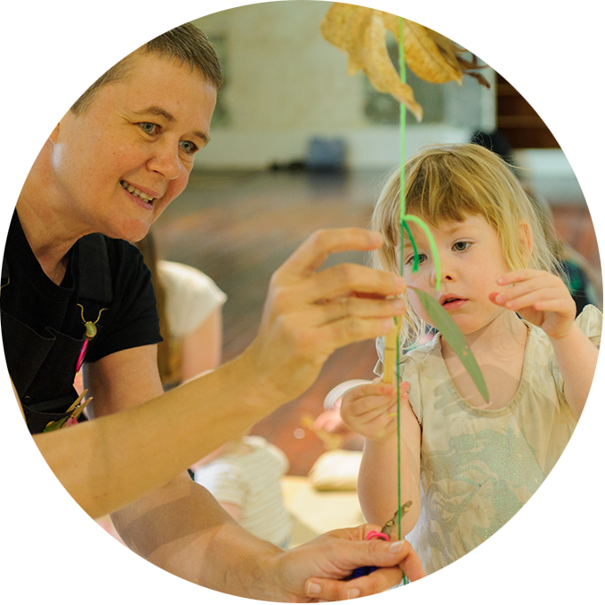 Art Tree production photo: Sarah Walker. A Polyglot artist and child play with a hanging string attached with leaves.
