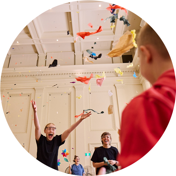 Whirlwind photo: A Polyglot artist opens their arms in joy as a child looks on. Confetti falls in the air. Photo: Laura May Grogan.