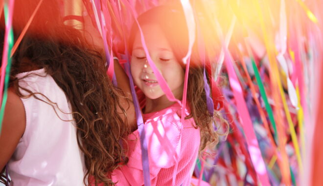 Tangle production photo: Ethan David, NYU Abu Dhabi Arts Center. A child in a pink t-shirt stands among hundreds of strands of colourful elastic, their eyes closed.