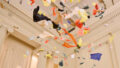 Whirlwind production photo: Laura May Grogan. Colourful paper confetti swirls in the air under an intricate heritage ceiling.