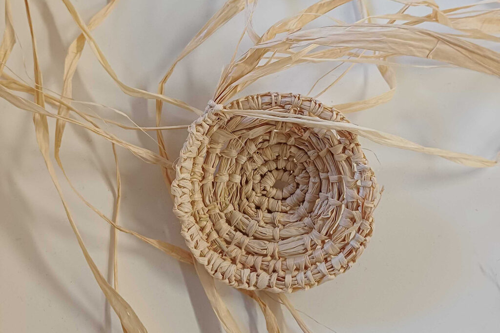 RAP Working Group & PIPS creative session photo: Cat Sewell. A small, partially woven raffia basket.